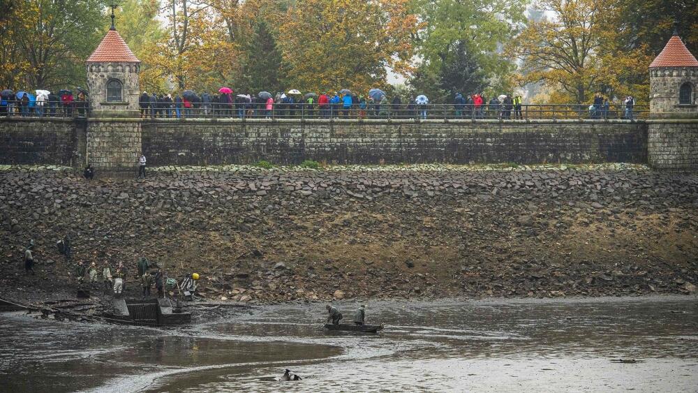 Výlov začal, ale diváci se vrhají ke druhému zábradlí. To podstatné se totiž náhle děje pod hrází, kde ryby hromadně prchají do Harcovského potoka. (Foto: Artur Irma)