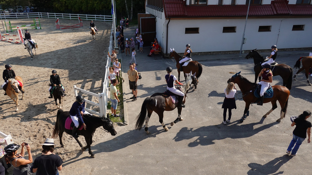 Jezdci na koních na každém kroku a mezi nimi trenéři, organizátoři a diváci.
